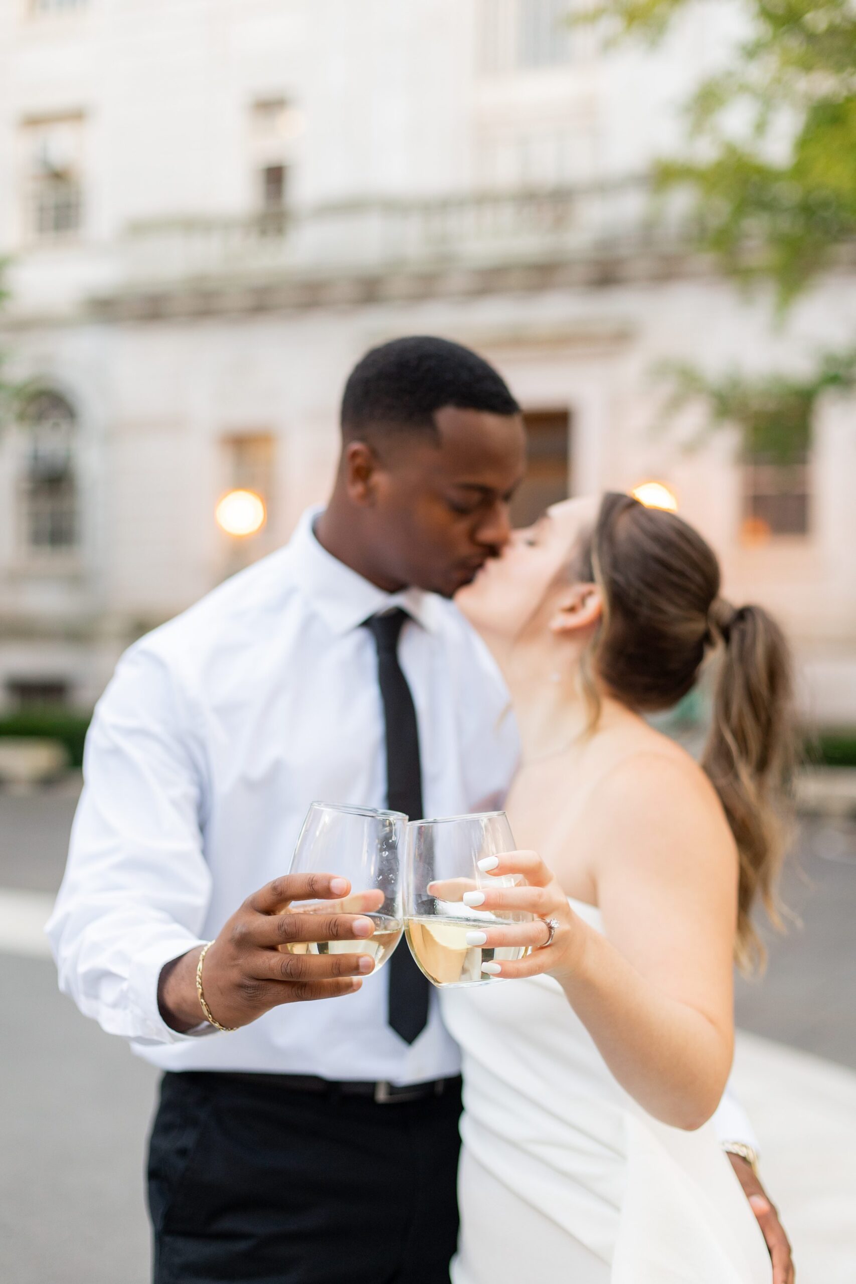 Couple popping champagne during engagement photos at Hartford City Hall